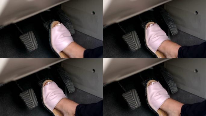 一个女人穿着夏天的鞋子的特写镜头在汽车上踩下了制动踏板。