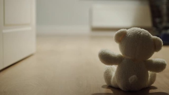 男子经过一个独自坐在地板上的小毛绒熊玩具
