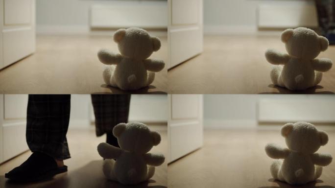 男子经过一个独自坐在地板上的小毛绒熊玩具