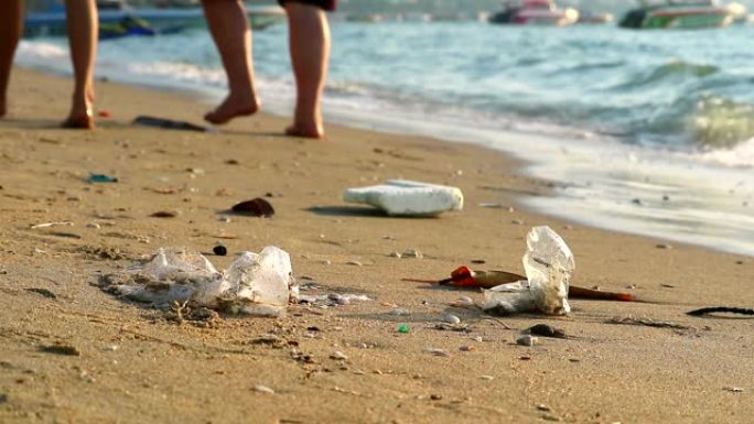 人们带着塑料橡胶在海滩上行走，废物留在海滩上，海浪把它们吹进海里