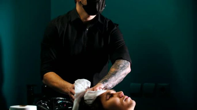 纹身的男人理发师使他的客户头发变干