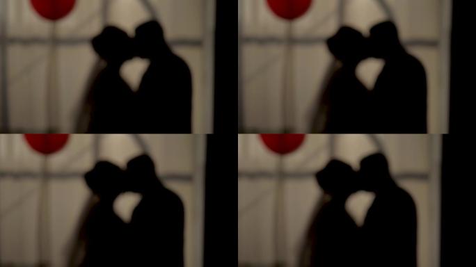 新娘和新郎在日落窗剪影拍摄的背景下浪漫地亲吻。中拍和慢动作