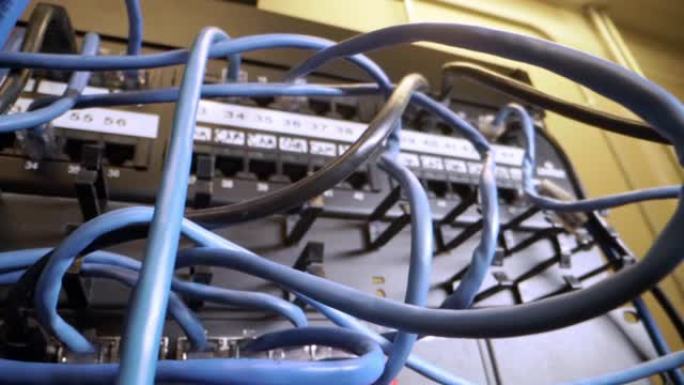 Cat5e以太网电缆插入闪烁的网络交换机中，在信息技术网络壁橱的背景中带有纠结的凌乱的高速互联网千兆