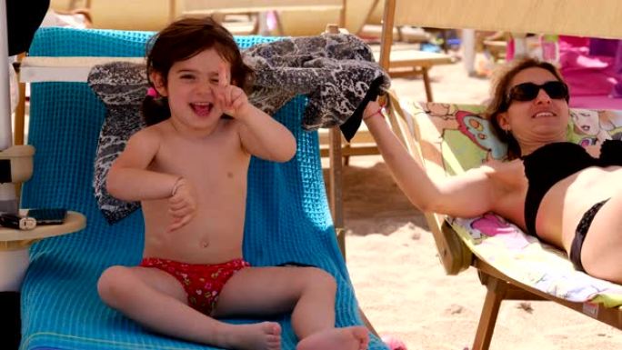 暑假期间，有趣的女婴和孩子们一起在沙滩椅上跳舞