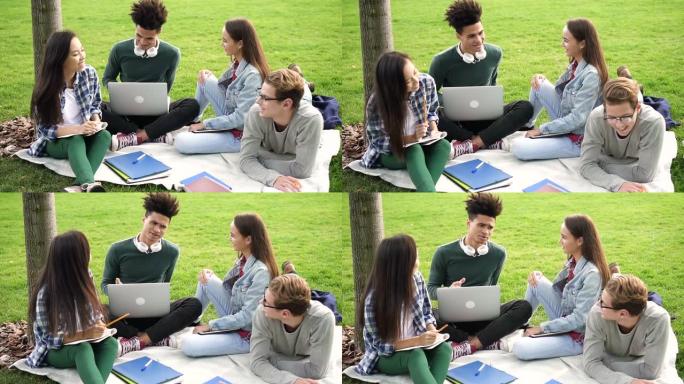 青年学生坐在草地上欢快地在一起聊天