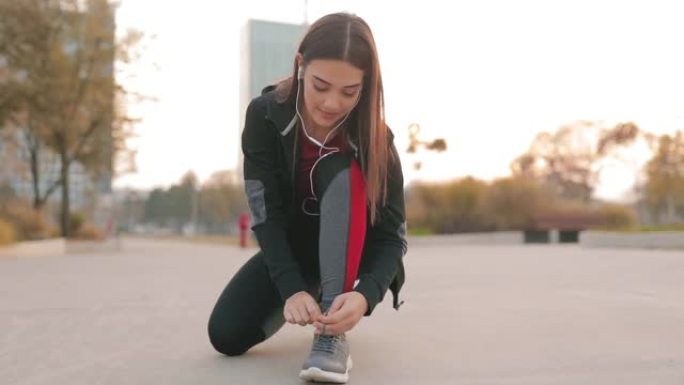 运动女人在城市公园绑跑鞋。