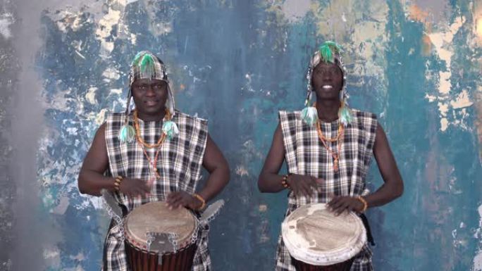 两名穿着五颜六色服装的非洲艺术家演奏djemba鼓