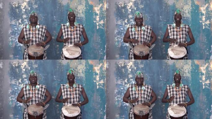两名穿着五颜六色服装的非洲艺术家演奏djemba鼓