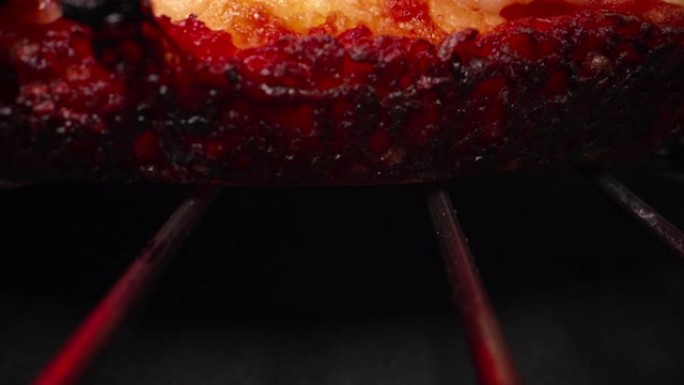 超特写广角微距拍摄烧焦的油炸外壳在美味的热腾腾的深盘意大利辣香肠比萨饼新鲜出炉在加热灯下的冷却架上，