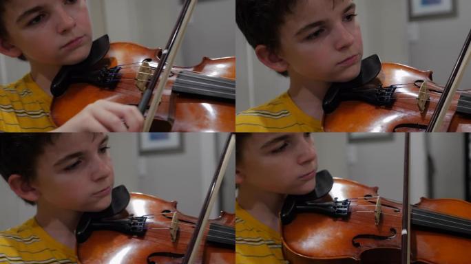 年轻的男孩神童在家里集中精力并拉小提琴