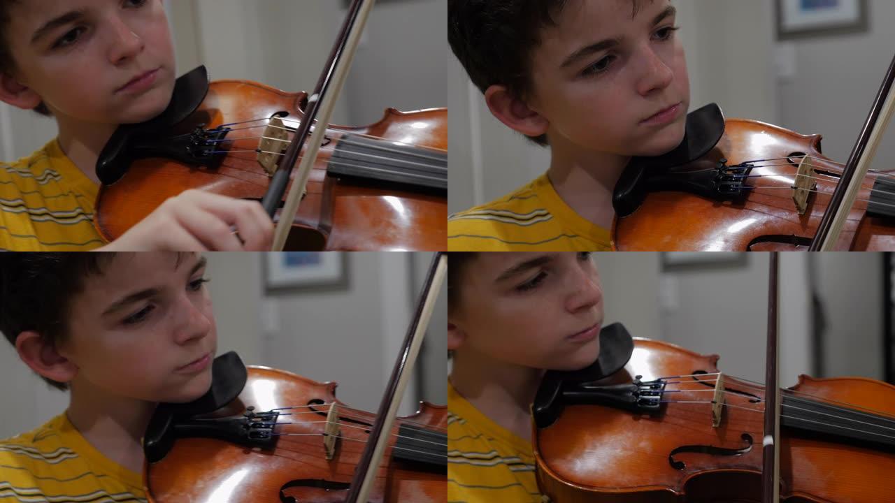年轻的男孩神童在家里集中精力并拉小提琴