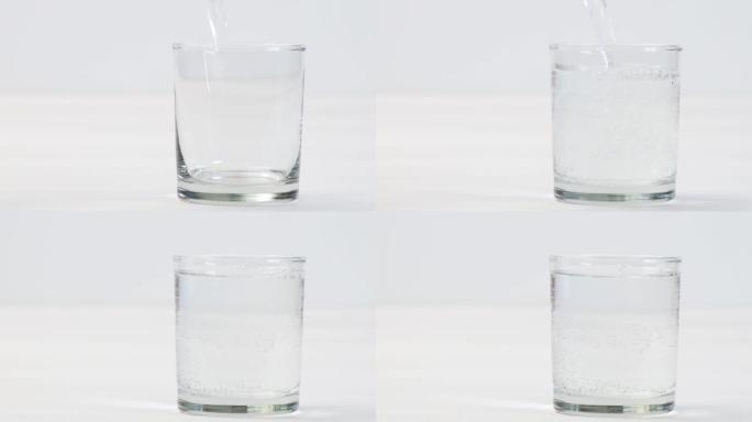特写镜头将水倒入白色背景的透明玻璃中。