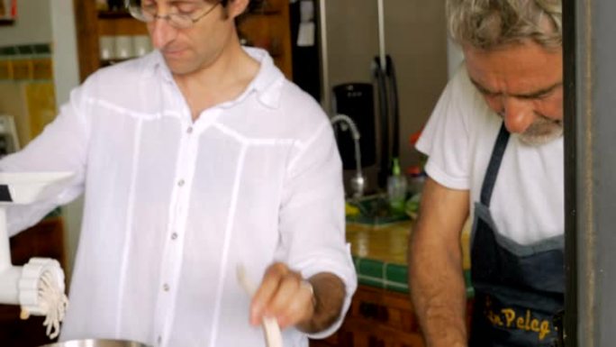 一个成熟的父子在厨房里一起为seder磨鱼