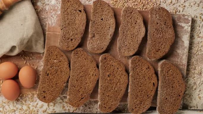 用手把面包片放在木板上。棕色有机面包