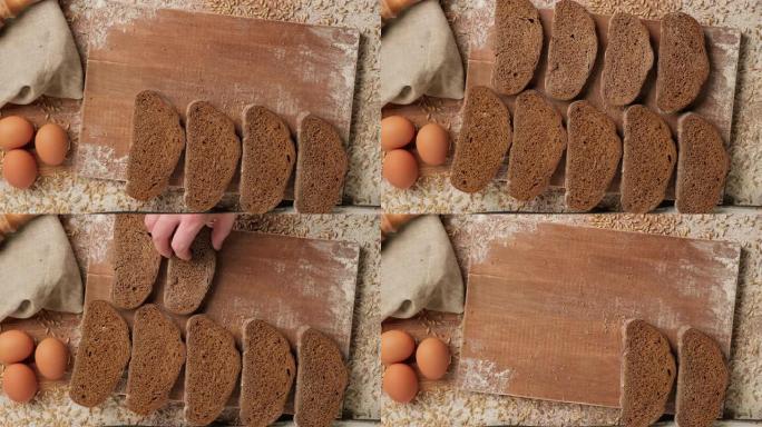 用手把面包片放在木板上。棕色有机面包