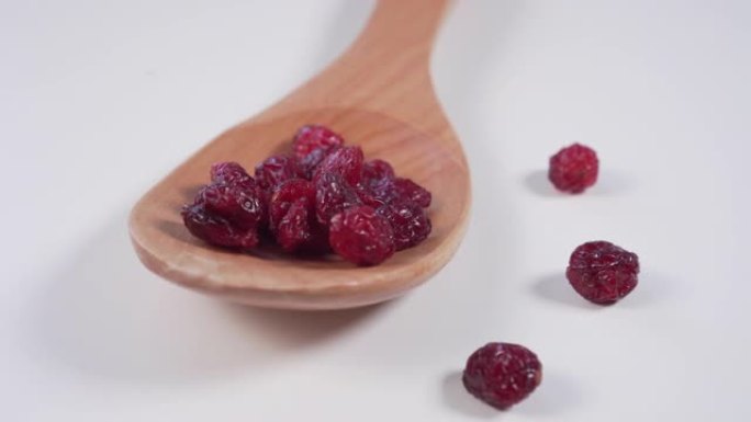 红色小红莓放在木勺里，散落在浅灰色的桌子上
