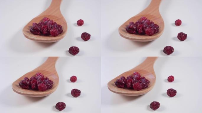 红色小红莓放在木勺里，散落在浅灰色的桌子上