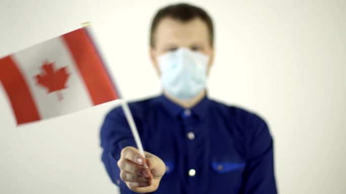一名男子脸上戴着防护面具，对着病毒挥舞着加拿大国家的国旗。国家冠状病毒疾病概念，COVID-2019