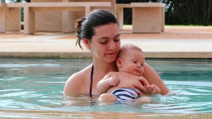 母亲在游泳池水中抱着新生婴儿