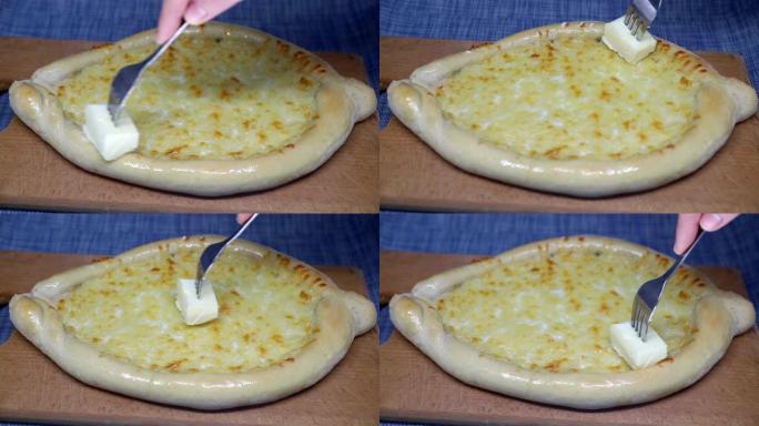 女人的手用叉子涂抹黄油khachapuri