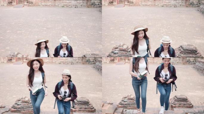 美丽的亚洲两个女人，拿着日记本和电影摄影机，她正在泰国世界遗产城市大城府散步。女人玩得开心，在老城度