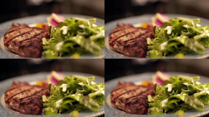 机架聚焦移动慢动作特写镜头，准备食用煮熟的，无骨的，调味的，多汁的里脊肉猪排，放在装有绿色沙拉和蔬菜