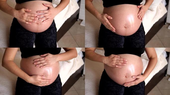 特写孕妇正在腹部涂抹保湿体油。