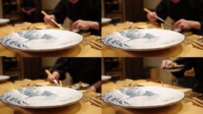 日本餐厅的一位厨师正在准备并在omagase美食课程中提供生鱼片，手工拍摄。