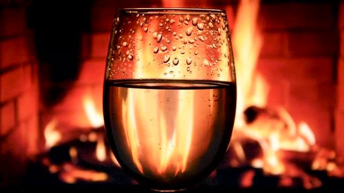 慢动作将白葡萄酒从瓶子倒入壁炉背景上的高脚杯中，精美的葡萄酒广告素材，欢呼声