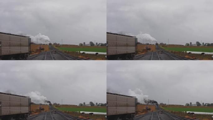 在雨天，一辆蒸汽机车将货物拉入院子，牛也看着烟和蒸汽