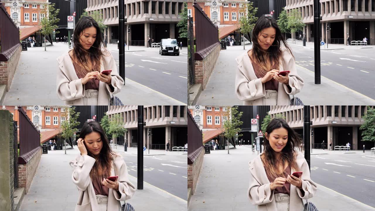 美丽的千禧一代长发中国女人在户外使用智能手机