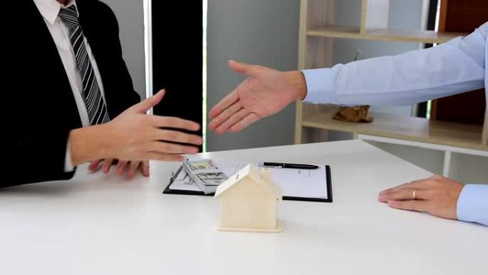 房屋销售代理商和买家致力于签署新房并握手。