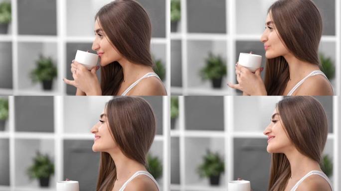 迷人的自然美女人喝咖啡盛杯。在4k红色相机上拍摄的特写镜头