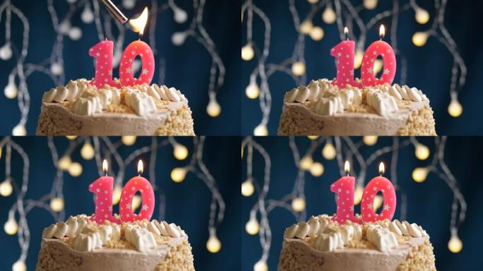 蓝色背景上有10号粉色蜡烛的生日蛋糕。蜡烛着火了。慢动作和特写视图