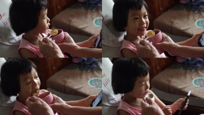 小女孩亚洲人在家里用智能手机吃饭
