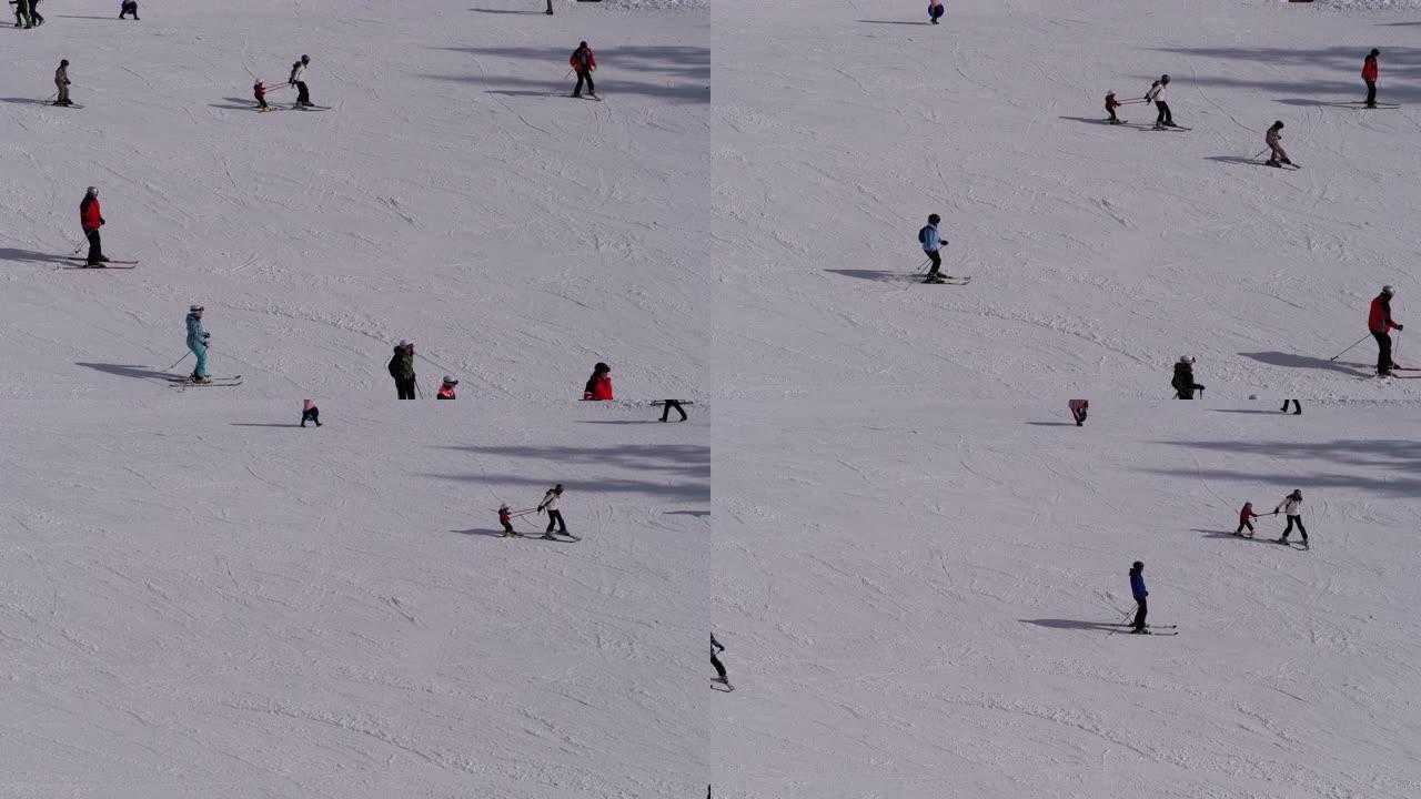 晴天，滑雪者和滑雪者在滑雪胜地的雪坡上骑行