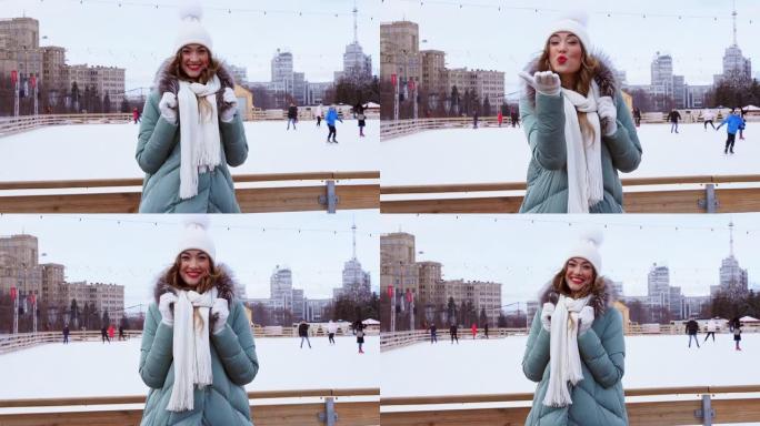 美丽可爱的中年女孩卷发保暖冬季夹克站在冰场背景城镇广场。