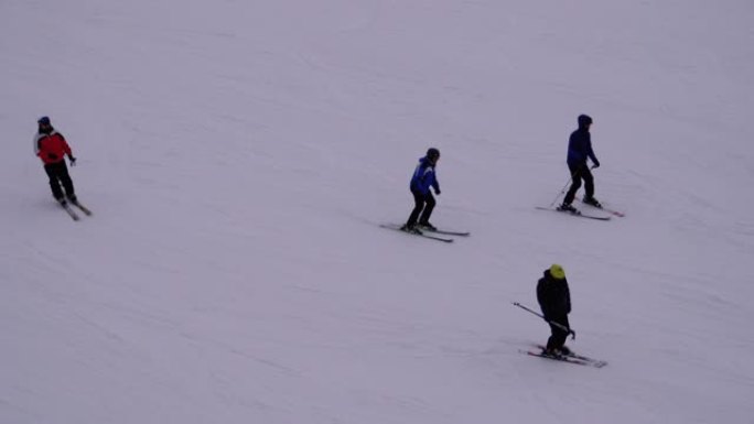 晴天，滑雪者和滑雪者在滑雪胜地的雪坡上骑行