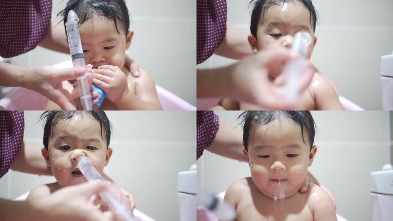 母亲在家里的浴缸里洗澡后用注射器冲洗儿子的鼻子。