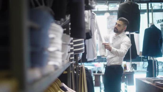 拉丁美洲男人在男装商店选择衬衫 (慢动作)