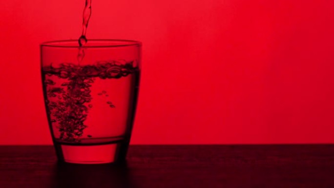 倒杯水-红色背景倒入透明玻璃杯水源