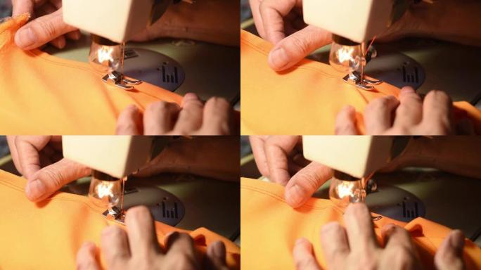 老妇人的手用橙色丝绸材料在老式缝纫机上缝制连衣裙特写