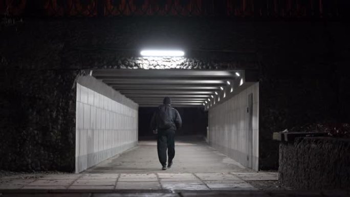 晚上，背着背包的人穿过人行地下通道。
