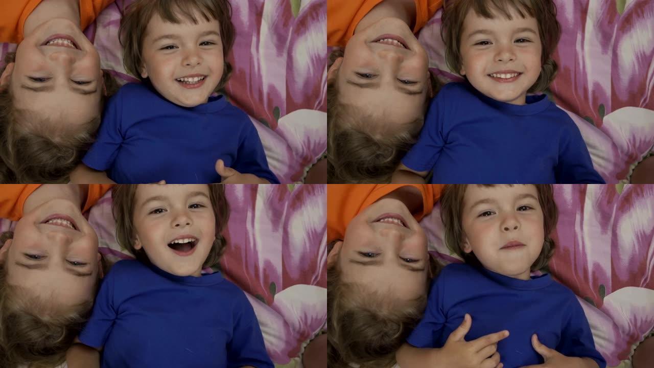 朋友自拍。兴奋的幼儿躺在床上玩耍，自拍。小弟弟和妹妹在镜头前偷偷地接吻。家人用智能手机自拍。特写。