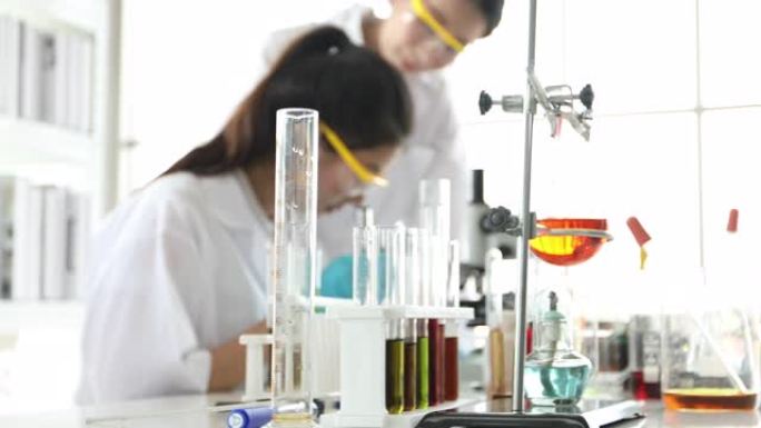 医学研究和科学家正在实验室中使用显微镜，片剂和试管，微量移液器和分析结果。