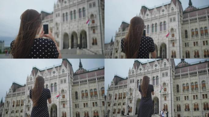 女孩在匈牙利布达佩斯的国会大厦拍摄手机照片