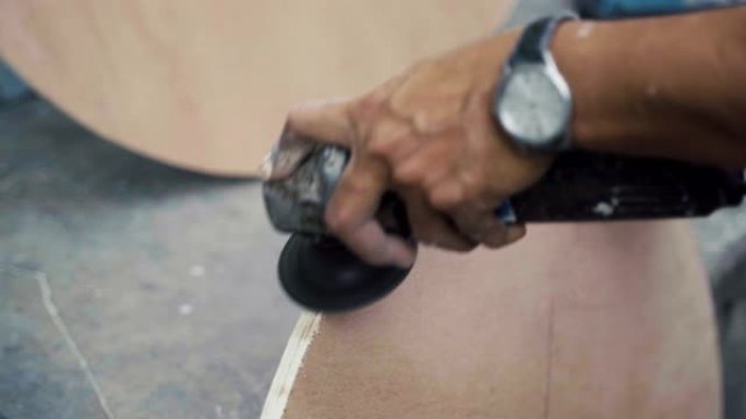 手工工人用电动磨床锯磨圆木材的特写。
