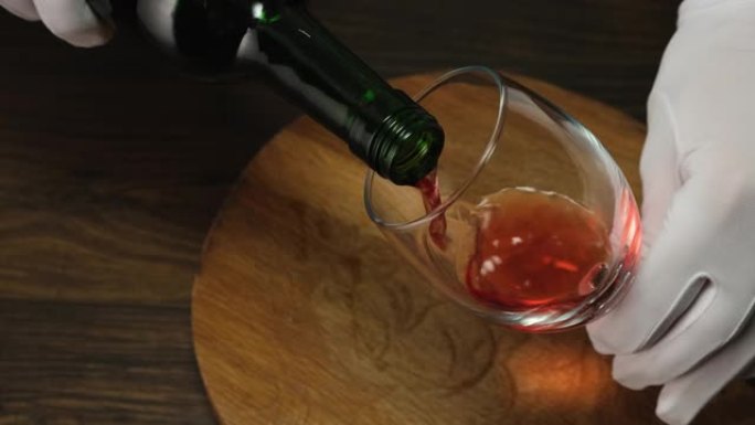 熟练的侍酒师将红酒从瓶子倒入玻璃杯中。特写。