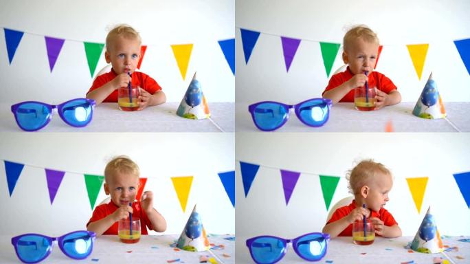 一个蹒跚学步的小男孩喝着橙汁庆祝自己的生日。万向节运动