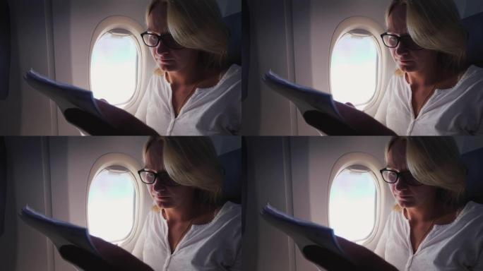 一名戴着眼镜的年轻女子在飞机上阅读文件
